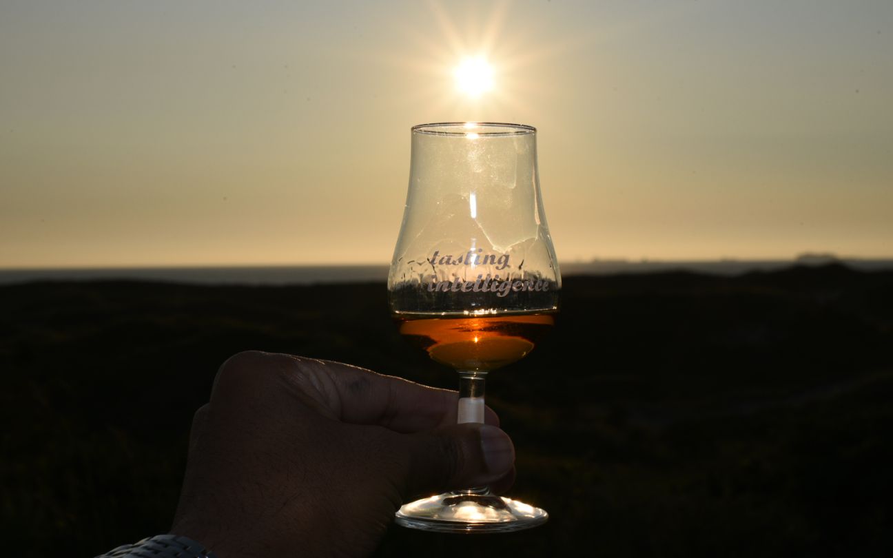 Whisky glass with text tasting intelligence during sunset filled containing an alcoholic beverage for a tasting